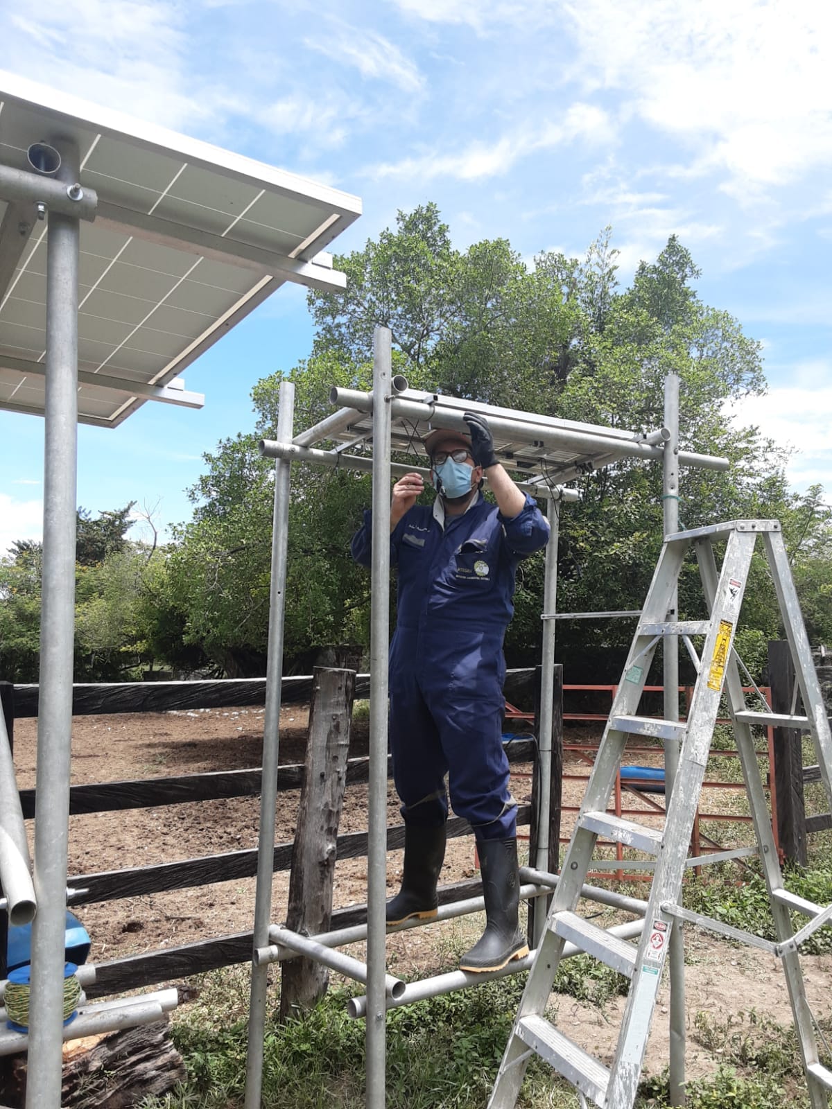 Técnico de INTEGRA instalando una estructura metálica con paneles solares junto a un corral