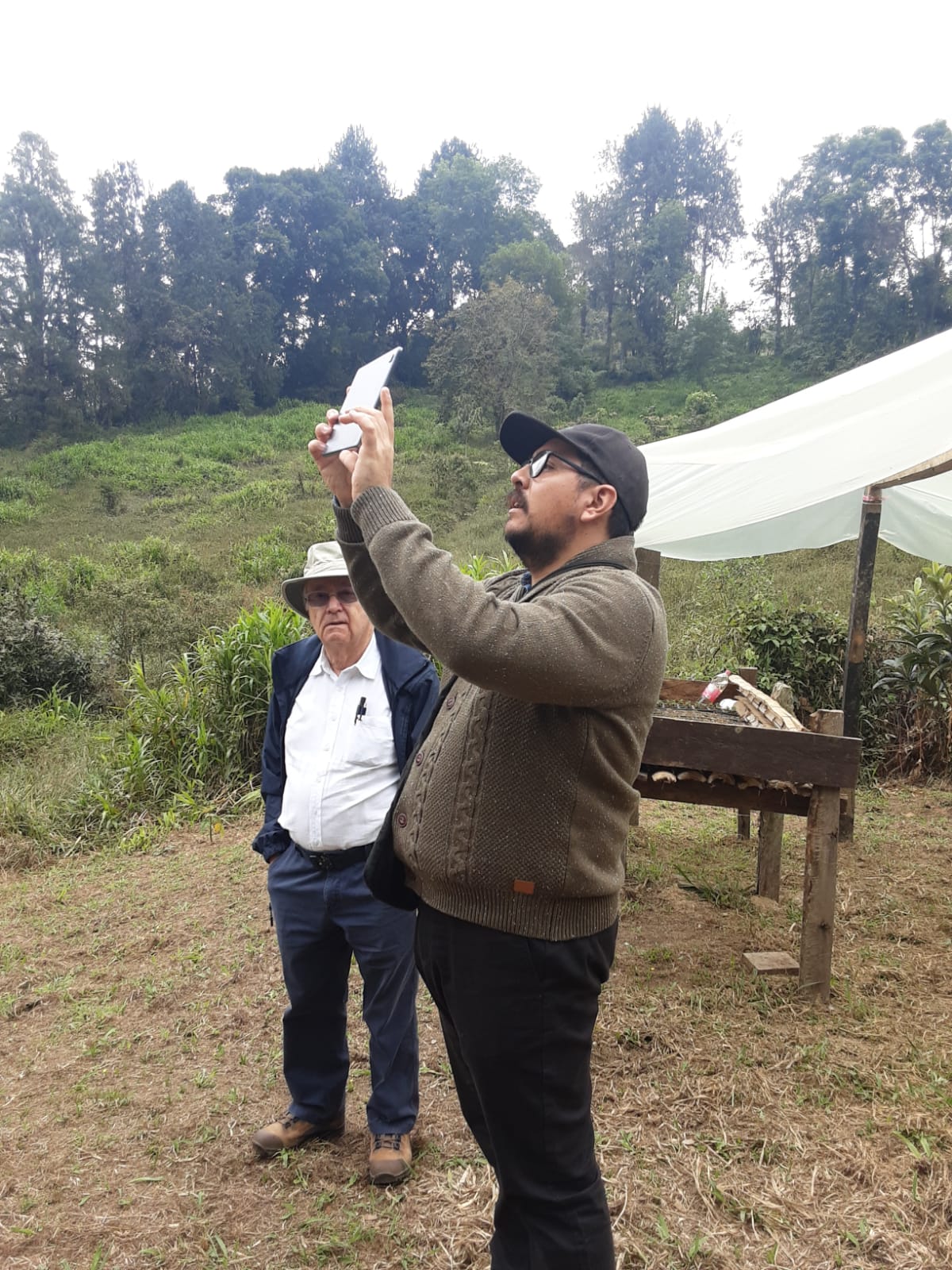 Ingeniero registrando con tableta el estado de un cultivo junto al productor