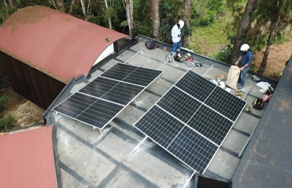 Cuadrilla instalando módulos fotovoltaicos sobre la cubierta de una vivienda rural