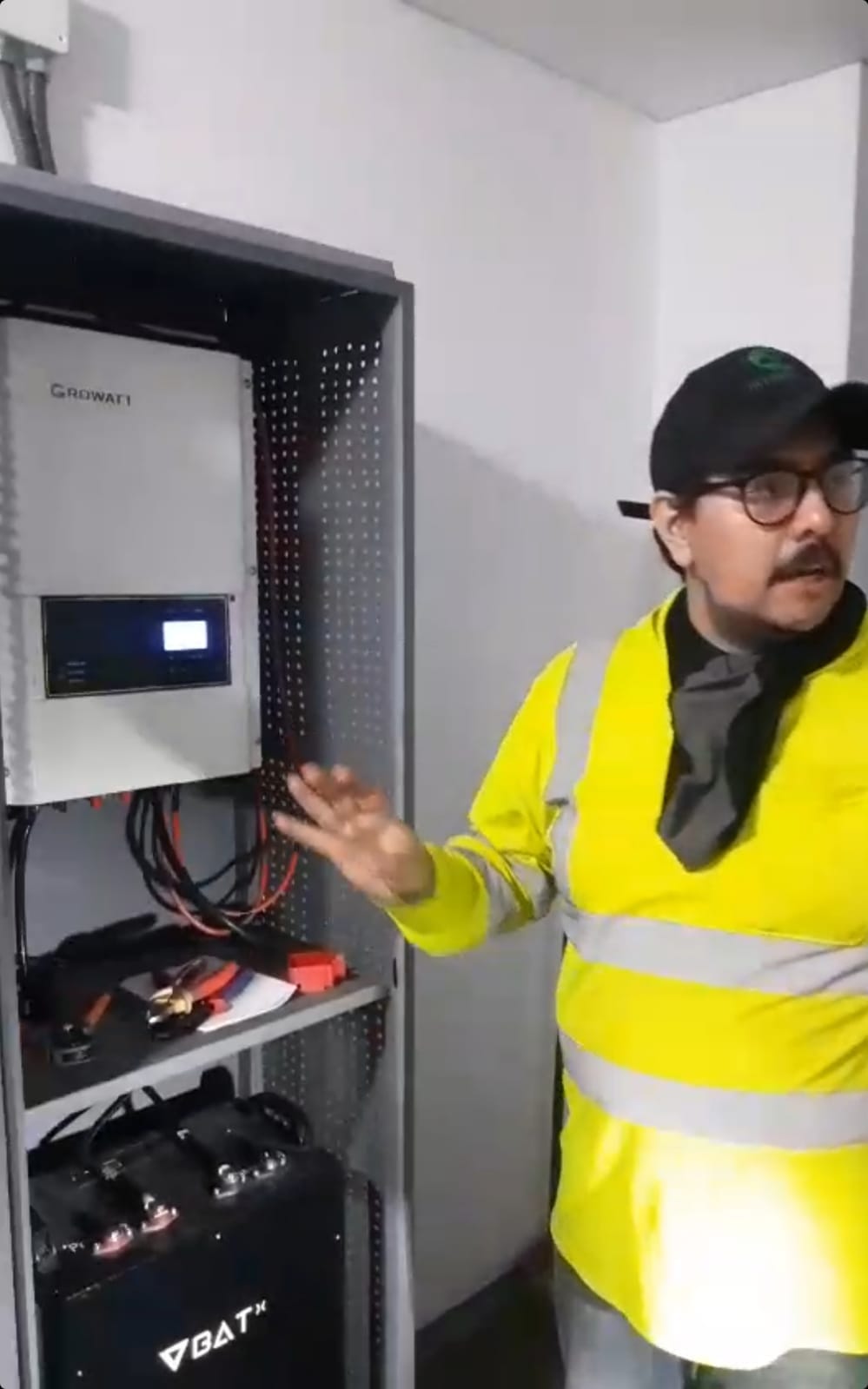Técnico explicando el inversor solar y el banco de baterías de litio de un sistema fotovoltaico